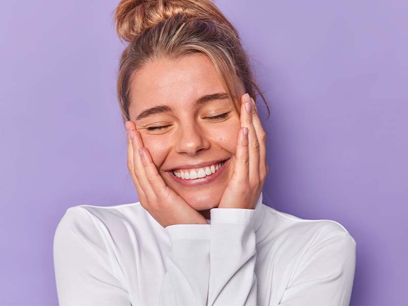 Woman smiling with her hands resting near her face